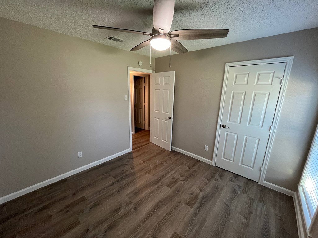 A room with a ceiling fan and two doors.
