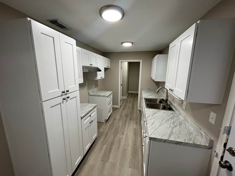 A small kitchen with white cabinets and a sink.