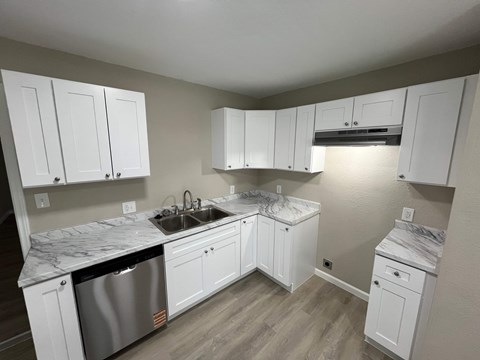 A kitchen with white cabinets and a marble countertop.