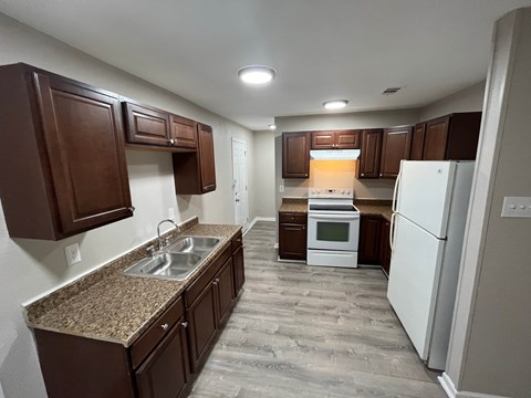 A kitchen with brown cabinets and a white refrigerator.