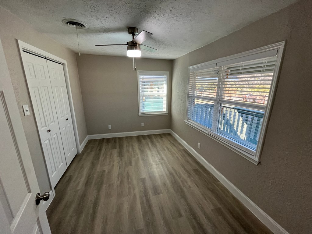 A room with a ceiling fan and a window with blinds.