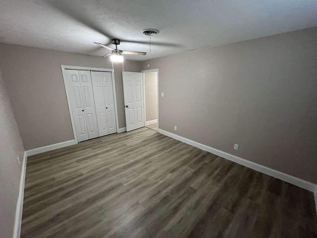 A room with a ceiling fan and two doors.