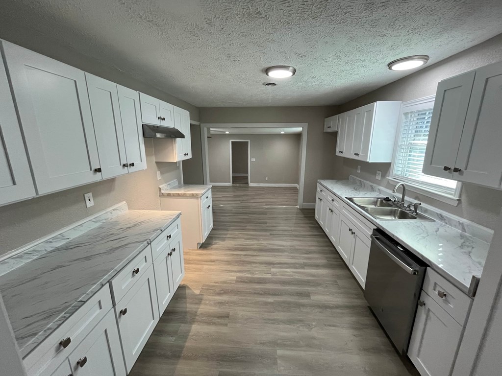 A kitchen with white cabinets and a wooden floor.