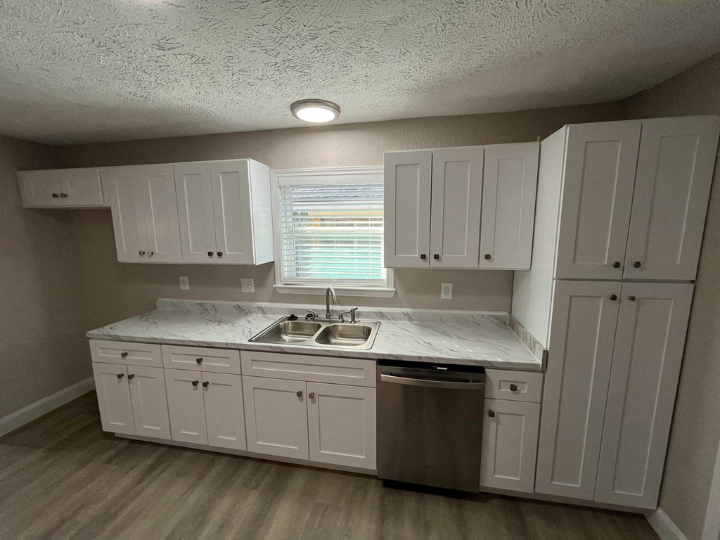 A kitchen with white cabinets and a marble countertop.