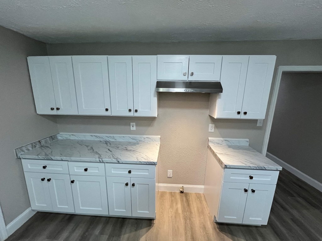 A kitchen with white cabinets and a marble countertop.