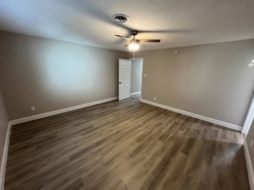 A room with a ceiling fan and wooden flooring.