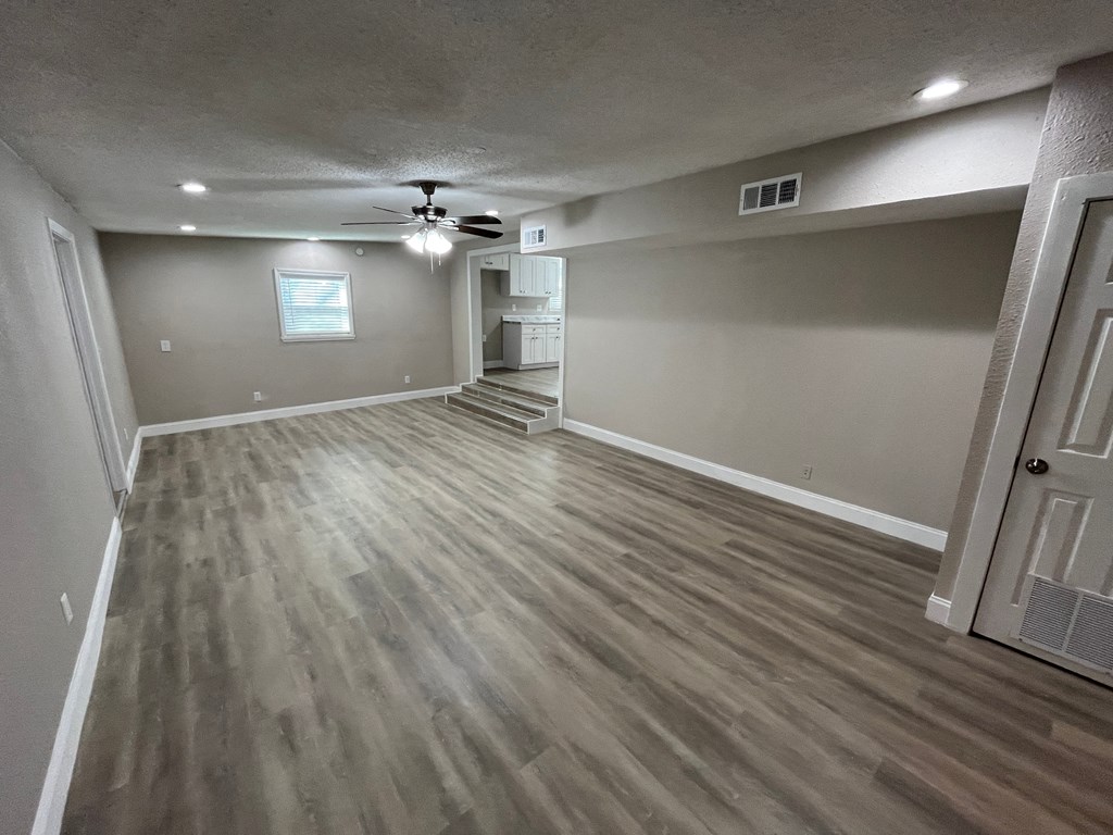 A room with wooden flooring and a ceiling fan.