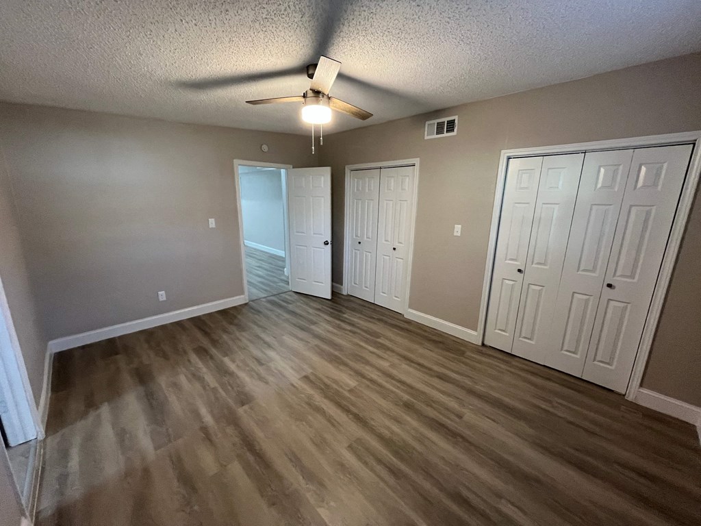 A room with a ceiling fan and light fixture, and three white doors.