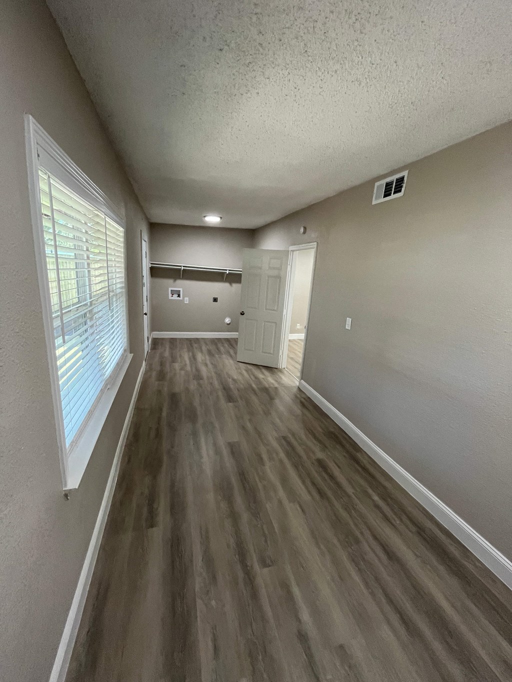 A long, narrow hallway with wood flooring and white walls.