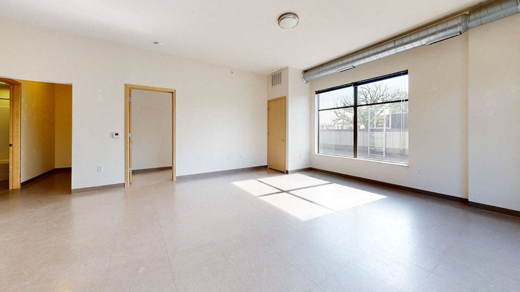 the living room of an empty apartment with a large window