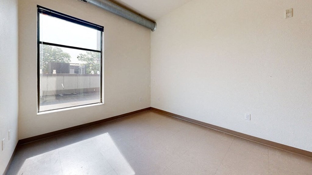 an empty room with a window and white walls