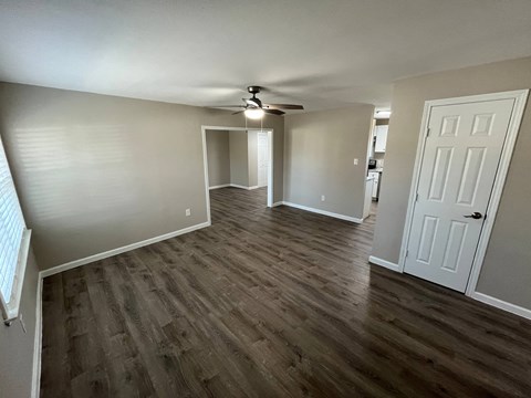 A room with a ceiling fan and wooden flooring.