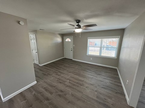 A room with a ceiling fan and a window with blinds.