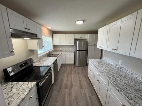A kitchen with white cabinets and a granite countertop.
