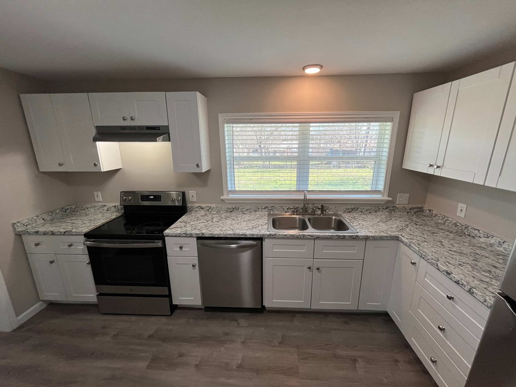 A kitchen with white cabinets and a marble countertop.