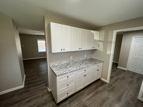 A kitchen with white cabinets and a marble island.