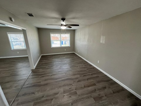 A room with a ceiling fan and wooden flooring.