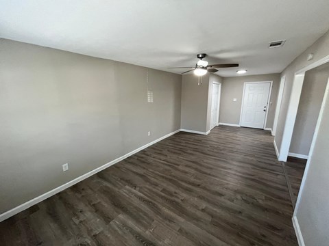 A room with a ceiling fan and wooden flooring.
