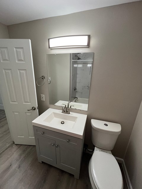 A bathroom with a white toilet, sink, and cabinet.