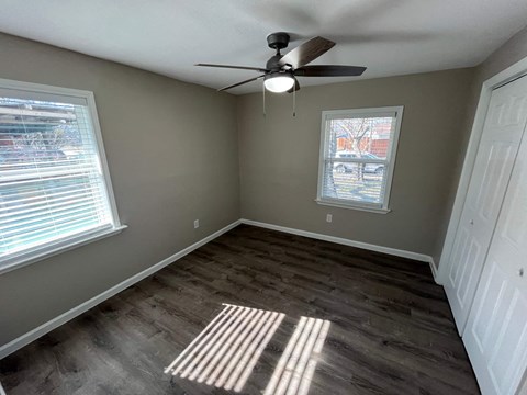 A room with a ceiling fan and a window letting in sunlight.