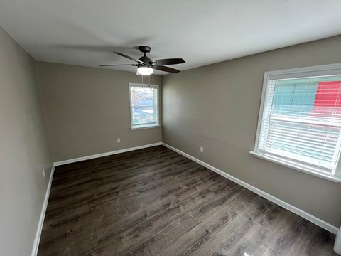 A room with a ceiling fan and a window with blinds.