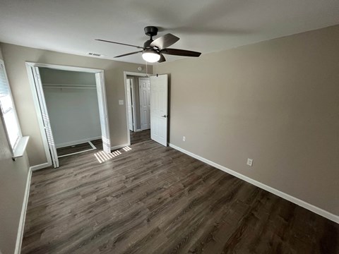 A room with a ceiling fan and wooden flooring.