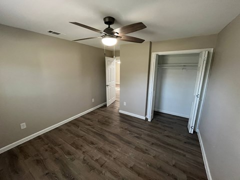 A room with a ceiling fan and wood flooring.