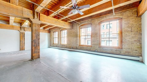 an empty room with a ceiling fan and brick walls