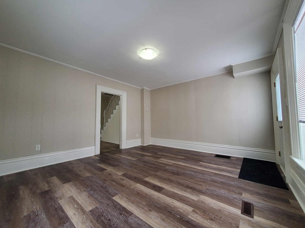 a living room with wood flooring and a door to a staircase