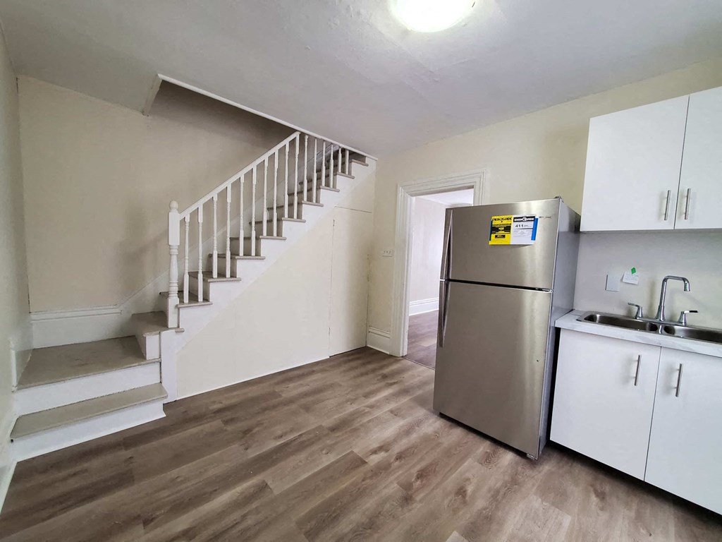 a kitchen with a stainless steel refrigerator next to a staircase