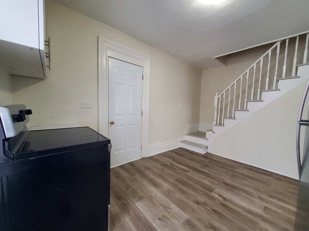 a room with a staircase and a refrigerator and a door