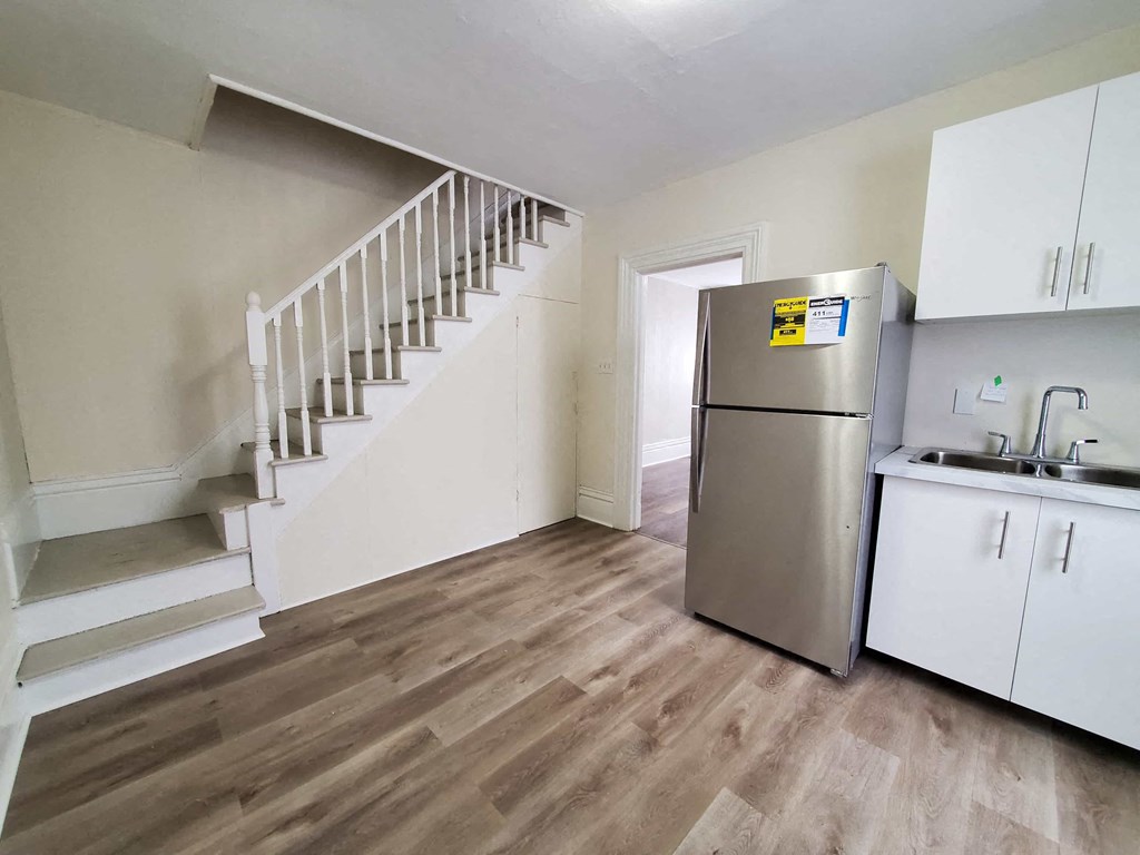 a kitchen with a stainless steel refrigerator and a staircase