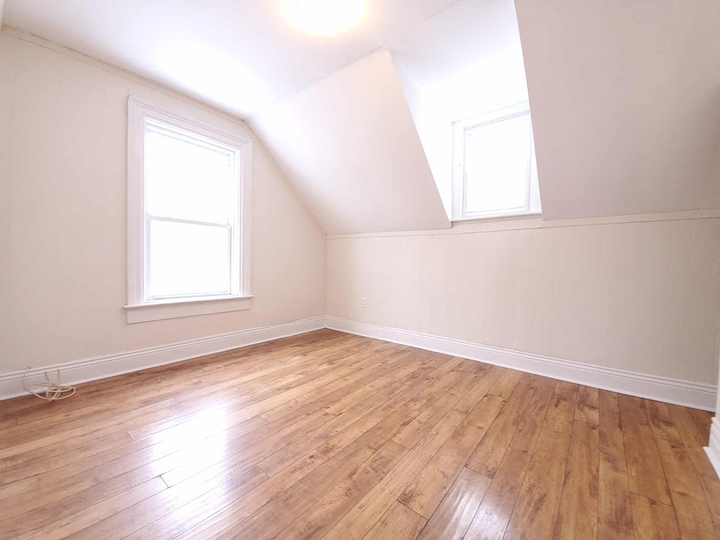an empty room with wood floors and two windows