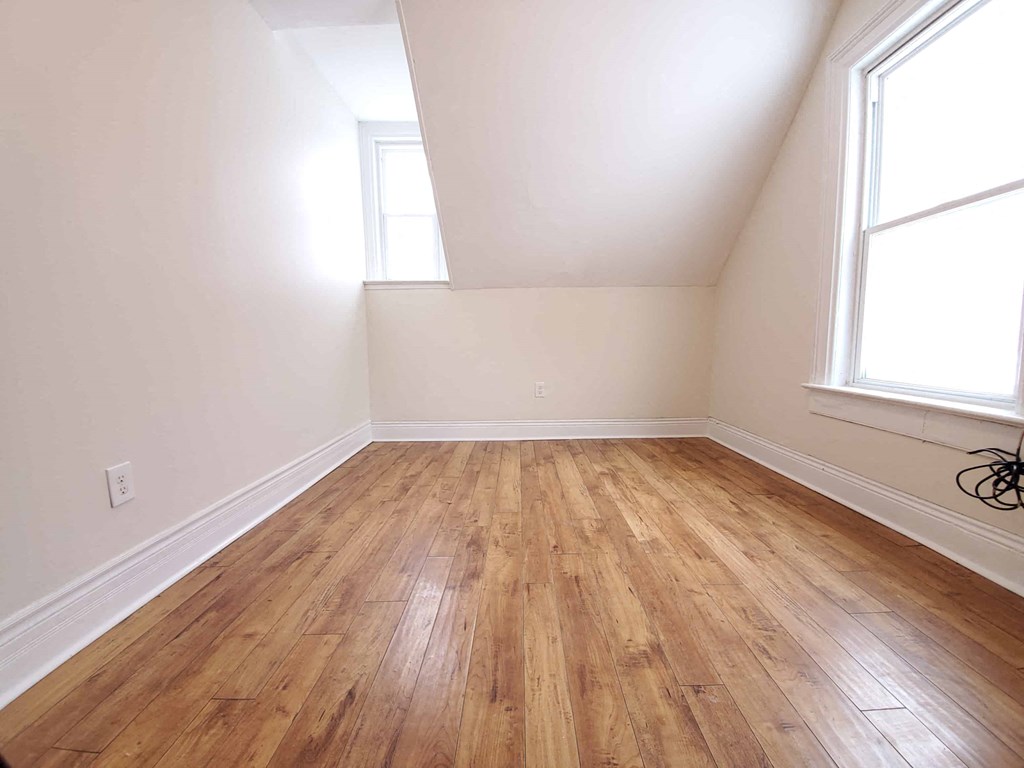a empty room with wooden floors and two windows