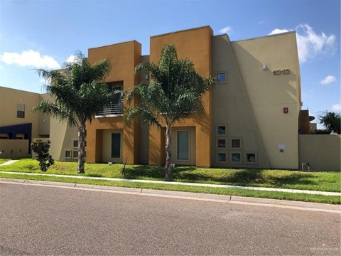 a building with palm trees in front of it on a street