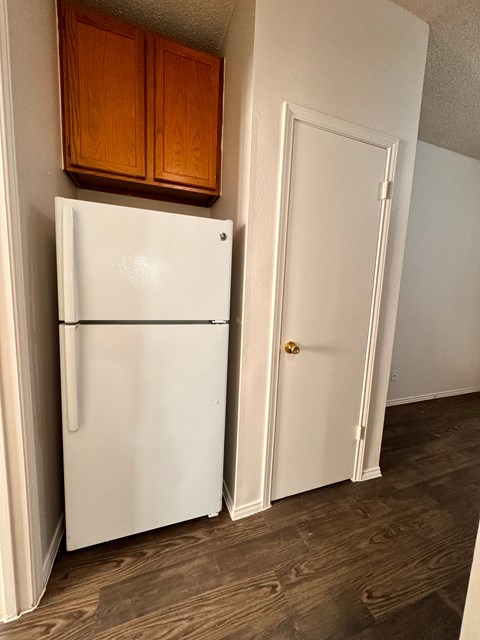 A white refrigerator is in a kitchen next to a white door.