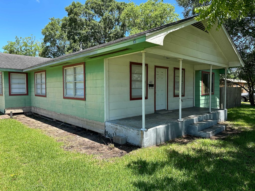 an old green and white house with a porch