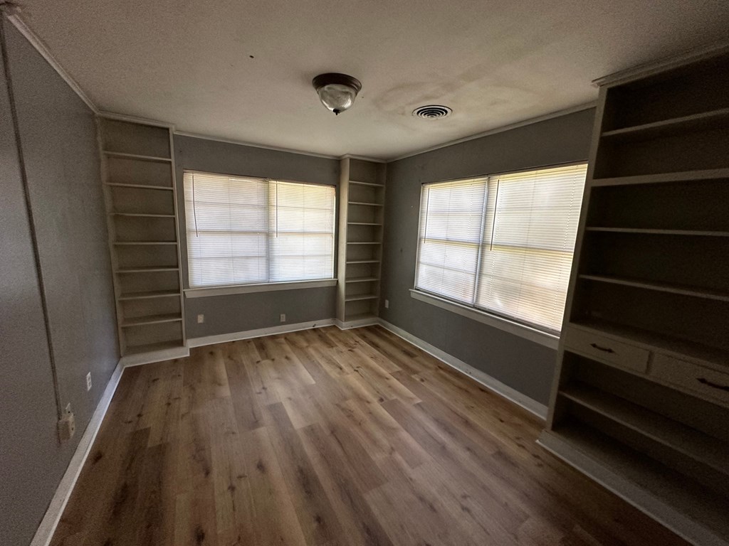 a room with wood floors and shelves and a window