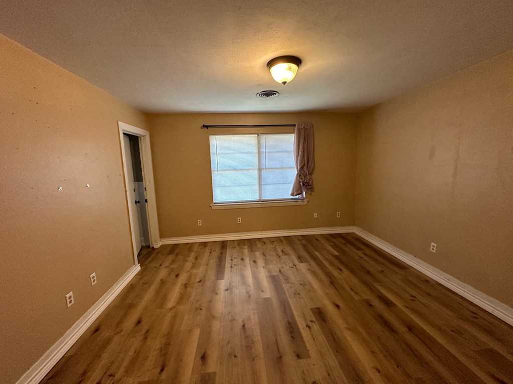 an empty living room with wooden floors and a window