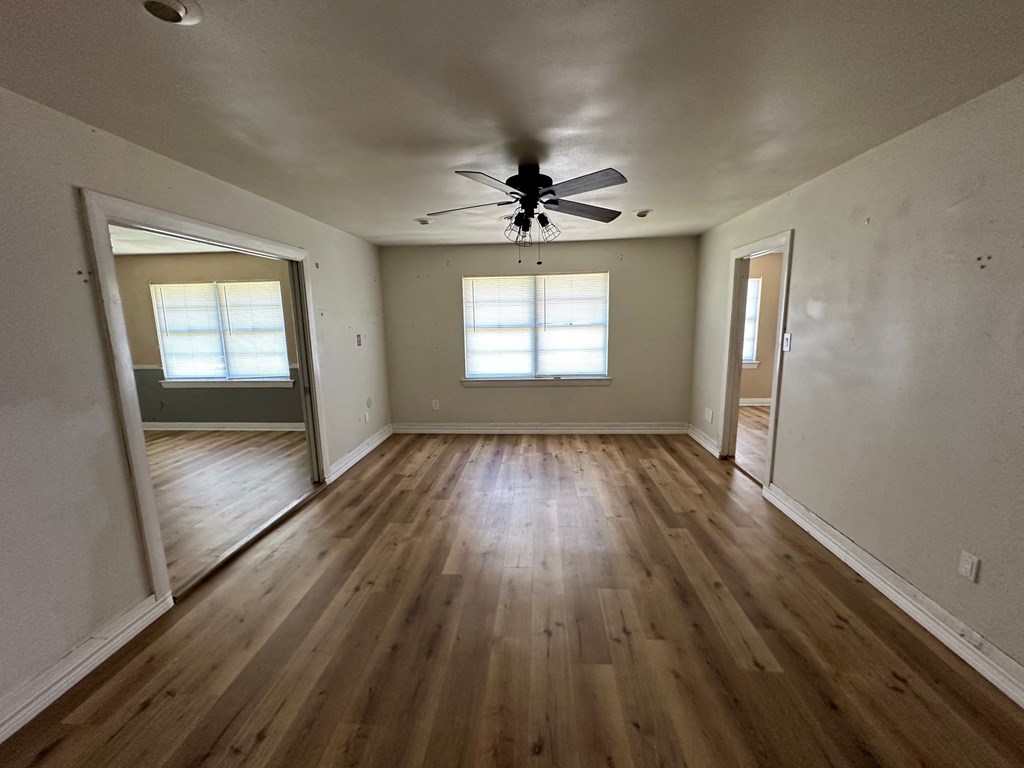 an empty living room with wooden floors and a ceiling fan