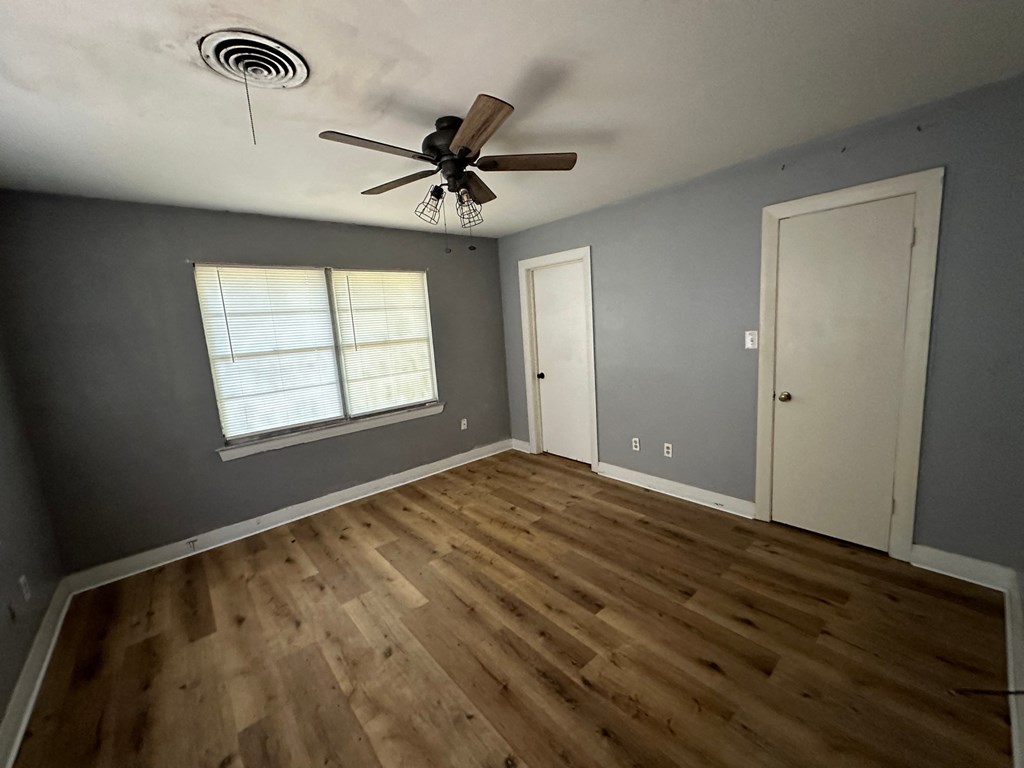 a living room with gray walls and wooden floors and a ceiling fan