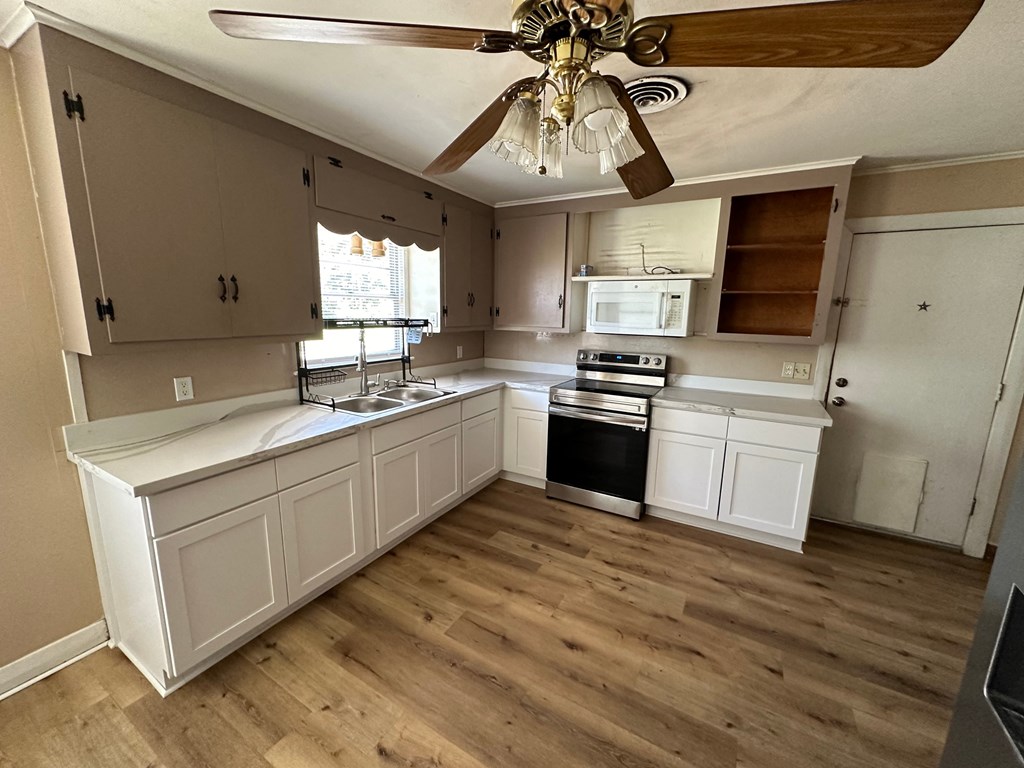 a remodeled kitchen with white cabinets and a ceiling fan