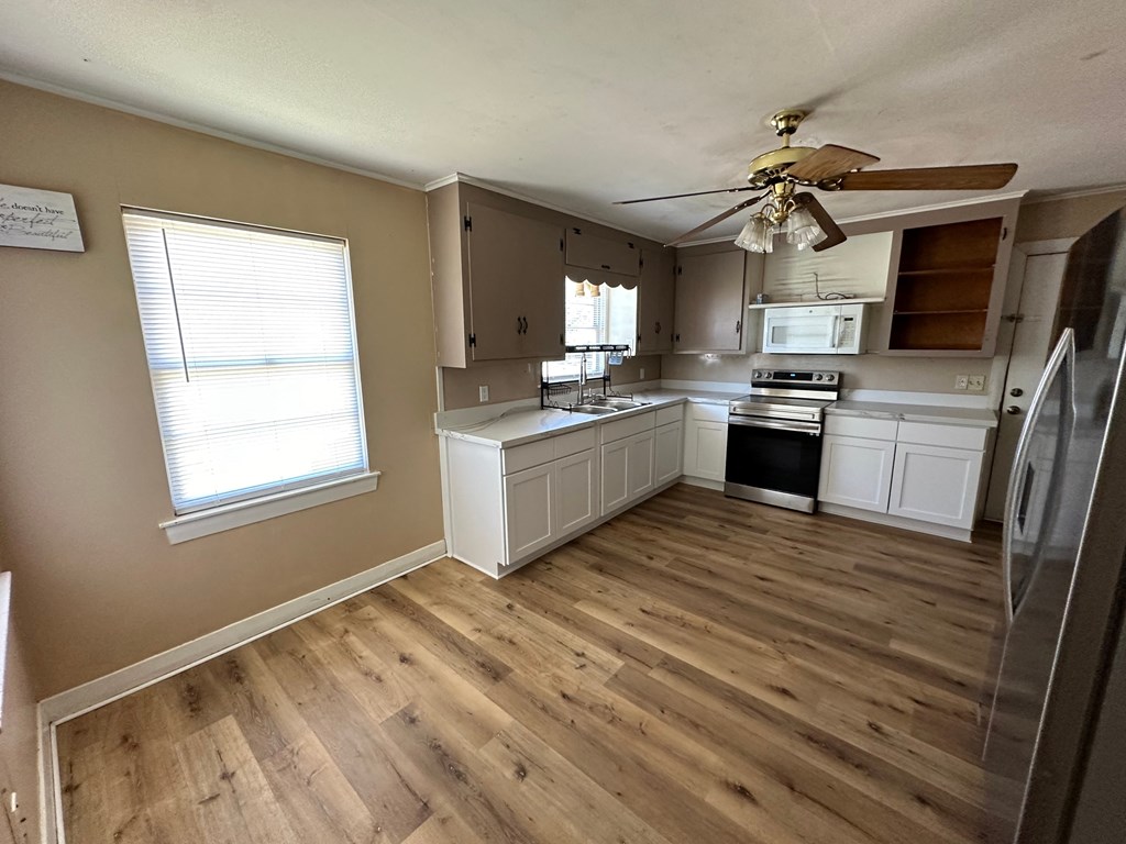 an empty kitchen with wooden floors and a ceiling fan
