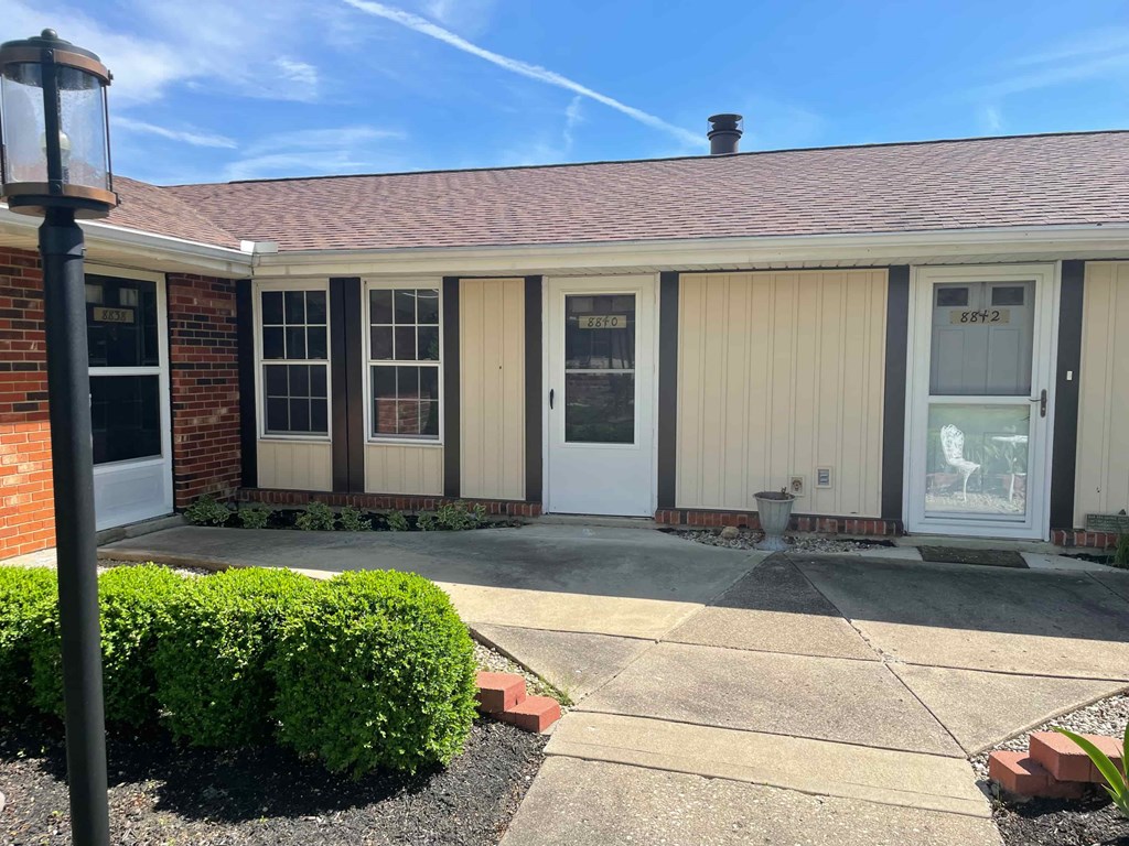 the front of a building with a walkway and a white door