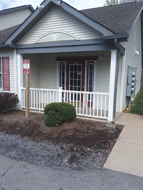 a house with a porch and a sign on the side of it