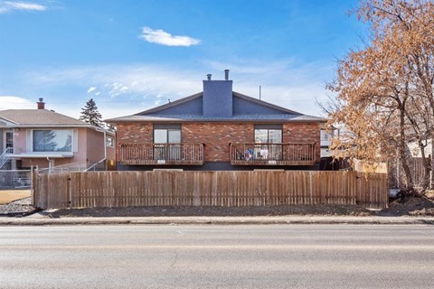 a brick house with two balconies behind a wooden fence