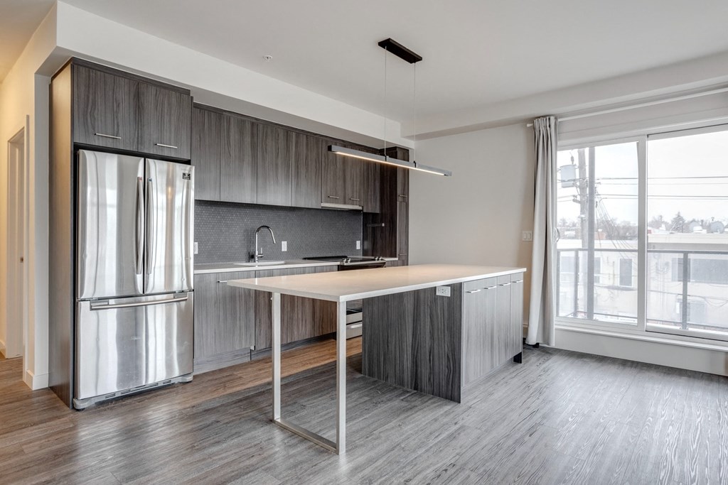 a kitchen with a large island and a stainless steel refrigerator