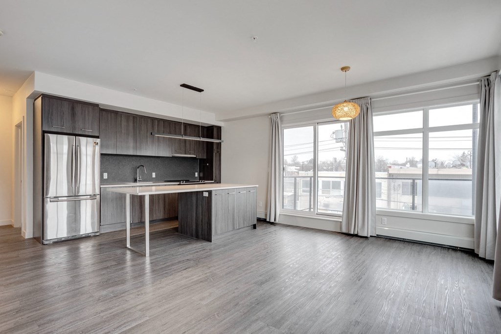 an empty kitchen with a large window and a stainless steel refrigerator