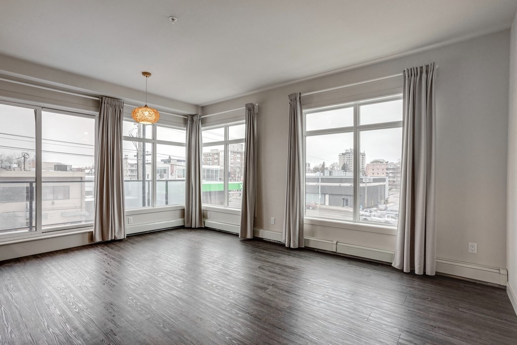 an empty living room with large windows and a city view