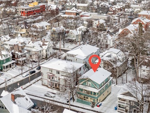 A red marker is on a green house in a snowy residential area.